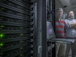 Computer science faculty members posing with rack of servers.