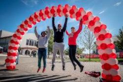 Alumni jumping under balloon arch